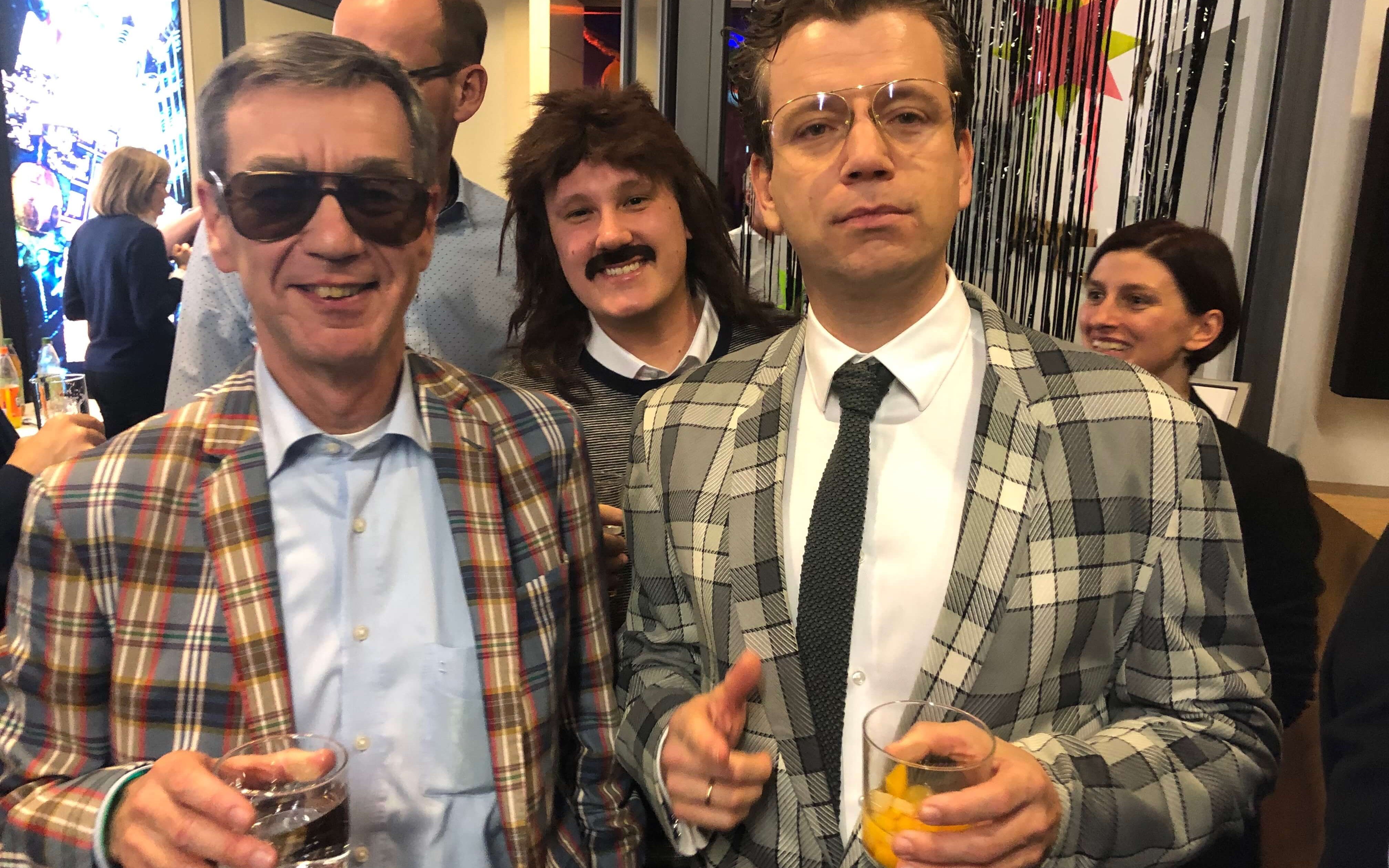 Fröhlich und sein Nachfolger als kaufmännischer Geschäftsführer, Klaus Hafemann (r.). Im Hintergrund: IW-Verteilungsforscher Maximilian Stockhausen. Das Bild entstand auf einer IW-Weihnachtsfeier mit dem Motto